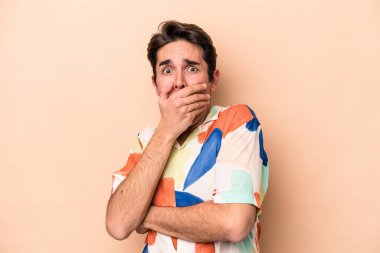 Beyazlı genç adam bej arka planda izole edilmiş korkmuş ve korkmuş..