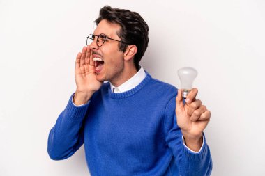 Beyaz arka planda izole edilmiş bir ampul tutan genç beyaz bir adam bağırıyor ve avuç içini açık tutuyor..