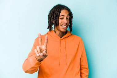 Genç Afrikalı Amerikalı adam mavi arka planda izole edilmiş. İki numarayı parmaklarıyla gösteriyor..