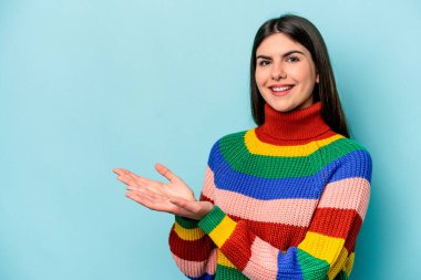 Mavi arka planda izole edilmiş beyaz bir kadın. Elinde palmiye ağacında bir kopya alanı var..