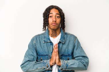 Genç Afrikalı Amerikalı adam beyaz arka planda izole edilmiş dua ediyor, bağlılık gösteriyor, dindar biri ilahi ilham arıyor..