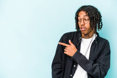 Genç Afrikalı Amerikalı adam mavi arka plan noktalarında izole edilmiş, başparmak uzakta, gülüyor ve kaygısız..