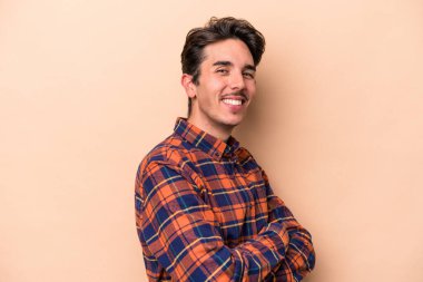 Beyazların arka planında izole edilmiş genç, kendinden emin, kararlılıkla kollarını kavuşturan bir adam..