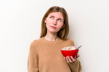 Beyaz arka planda izole edilmiş mısır gevreği yiyen genç İngiliz kadın hedeflerine ve amaçlarına ulaşmayı hayal ediyor.