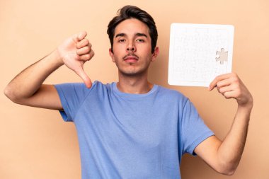 Beyazlı genç bir adam bej arka planda izole edilmiş bir yapboz tutuyor. Hoşlanmadığı bir hareket gösteriyor. Anlaşmazlık konsepti.