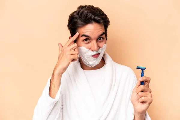 Young Caucasian Man Shaving His Beard Isolated Beige Background Pointing — Stock Photo, Image