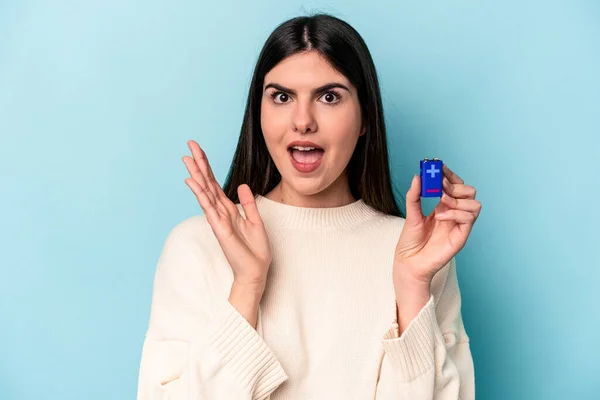 Mladá Běloška Žena Drží Baterii Izolované Modrém Pozadí Překvapené Šokované — Stock fotografie