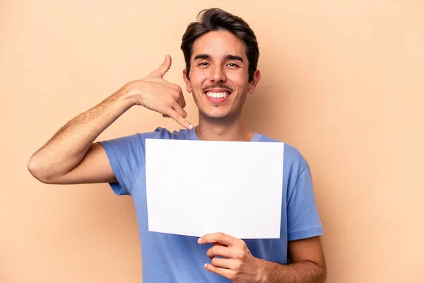 Ung Kaukasier Man Håller Skylt Isolerad Beige Bakgrund Visar Mobiltelefon — Stockfoto