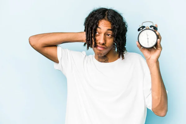 Jovem Afro Americano Segurando Despertador Isolado Fundo Azul Tocando Parte — Fotografia de Stock