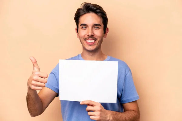 Jovem Caucasiano Segurando Cartaz Isolado Fundo Bege Sorrindo Levantando Polegar — Fotografia de Stock