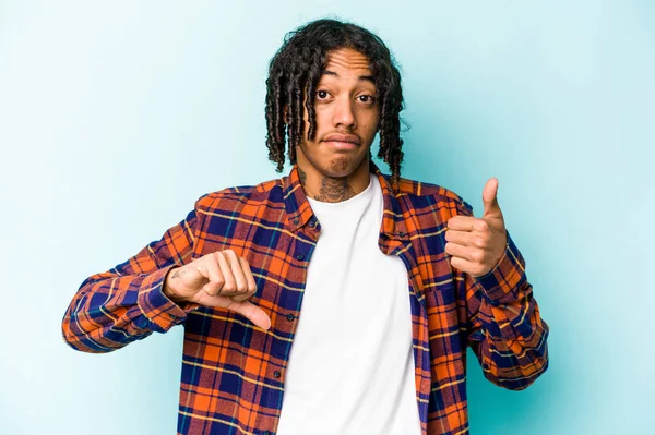 Genç Afro-Amerikalı adam mavi arka planda izole edilmiş, baş parmağını kaldırıyor, zor seçim konsepti