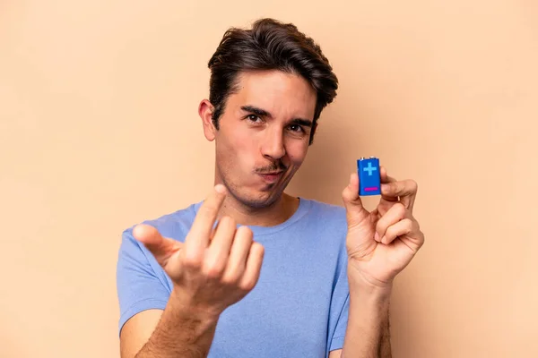 Mladý Běloch Drží Baterii Izolovanou Béžovém Pozadí Ukazuje Prstem Vás — Stock fotografie
