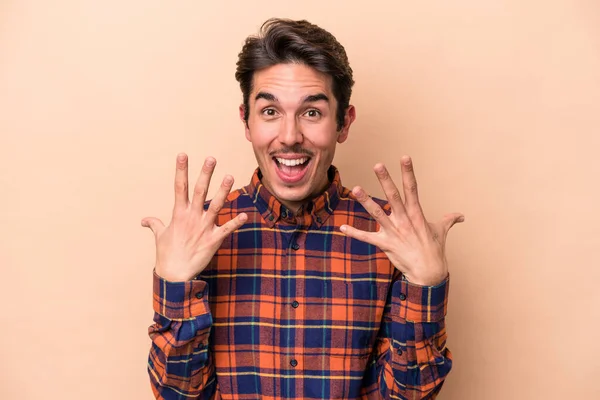 Junger Kaukasier Isoliert Auf Beigem Hintergrund Der Die Zahl Zehn — Stockfoto