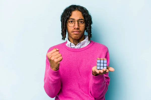 Mladý Afroameričan Drží Kostku Rubiks Izolovanou Modrém Pozadí Ukazující Pěst — Stock fotografie