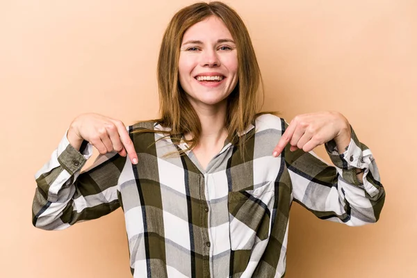 Young English woman isolated on beige background points down with fingers, positive feeling.