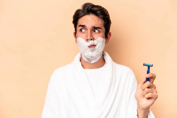 Young Caucasian Man Shaving His Beard Isolated Beige Background Confused — Stock Photo, Image