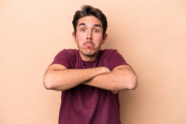 Beyazlı genç adam bej arka planda izole edilmiş omuzlarını silkeliyor ve gözleri açık..