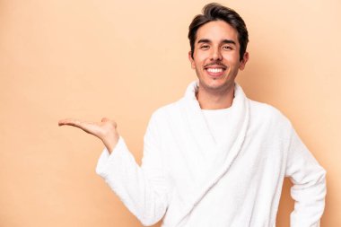 Kafkasyalı genç bir adam bej arka planda izole edilmiş bir şekilde avuçta fotokopi alanı ve belinde başka bir el tutuyor..