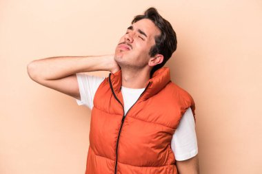 Beyazlı genç adam bej arka planda izole edilmiş dirsek masajı yapıyor, kötü bir hareketin ardından acı çekiyor..