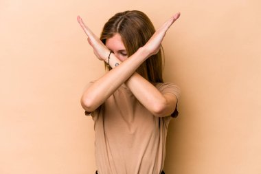 Genç İngiliz kadın bej arka planda izole edilmiş iki kolu çapraz tutuyor, inkar kavramı.