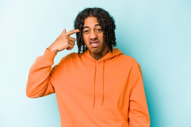 Genç Afrikalı Amerikalı adam mavi arka planda izole edilmiş kulakları elleriyle kapatıyor..
