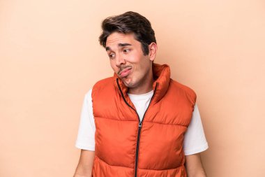 Beyazlı genç adam bej arka planda izole edilmiş omuzlarını silkeliyor ve gözleri açık..