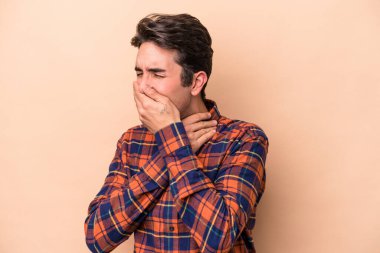 Beyazlı genç bir adam bej arka planda virüsten ya da enfeksiyondan boğaz ağrısı çekiyor..