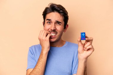 Elinde bej arka planda izole edilmiş, tırnak yiyen, gergin ve tedirgin bir baterist tutan genç beyaz adam..