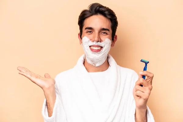 Young Caucasian Man Shaving His Beard Isolated Beige Background Showing — Stock Photo, Image