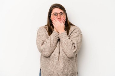 Beyaz arka planda izole edilmiş beyaz kilolu genç bir kadın elleriyle ağzını kapatırken şok oldu..