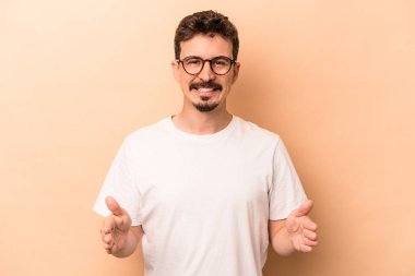 Beyazların arka planında izole edilmiş genç beyaz bir adam iki eliyle bir şey tutuyor, ürün sunumu..