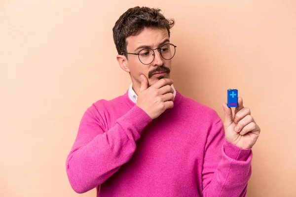 Jeune Homme Caucasien Tenant Des Batteries Isolées Sur Fond Beige — Photo