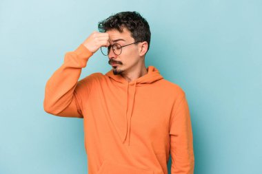 Kafkasyalı genç bir adam mavi arka planda izole edilmiş, başı ağrıyor, yüzüne dokunuyor..