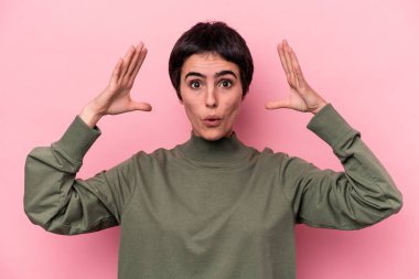 Pembe arka planda izole genç beyaz kadın zaferi ya da başarıyı kutluyor, şaşırıyor ve şok oluyor..