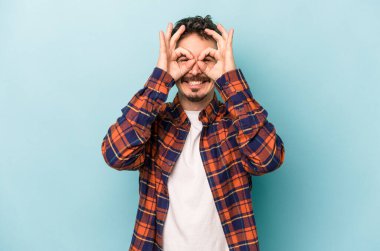 Kafkasyalı genç adam mavi arka planda izole edildi. Heyecanlı görünüyor..