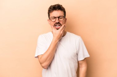 Beyazlı genç bir adam bej arka planda izole edilmiş güçlü bir diş ağrısı ve azı dişi ağrısı var..