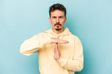 Mavi arka planda izole edilmiş genç beyaz bir adam bir mola hareketi gösteriyor..
