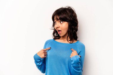 Beyaz arka planda izole edilmiş genç İspanyol kadın parmağını göstererek şaşırdı, geniş bir gülümsemeyle..