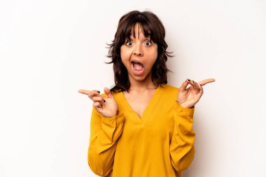 Young hispanic woman isolated on white background pointing to different copy spaces, choosing one of them, showing with finger.