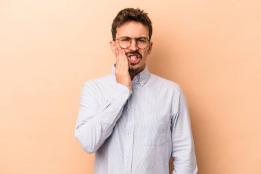 Beyazlı genç bir adam bej arka planda izole edilmiş güçlü bir diş ağrısı ve azı dişi ağrısı var..