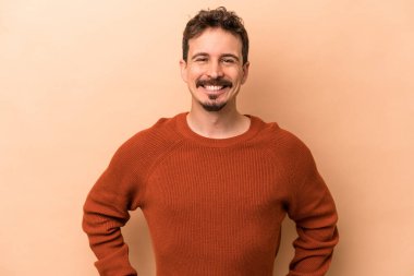 Beyaz tenli genç adam bej arka planda izole edilmiş mutlu, güler yüzlü ve neşeli.