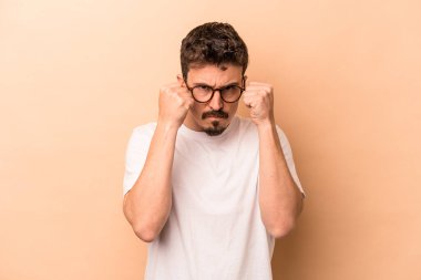 Beyazlı genç bir adam bej arka planda izole edilmiş. Yumruk atıyor, sinirleniyor, tartışıyor, boks yapıyor..