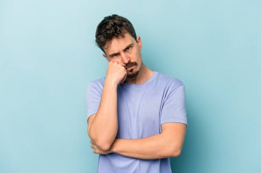 Mavi arka planda izole edilmiş genç beyaz adam tekrarlanan bir görevden yoruldu..