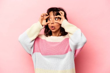 Pembe arka planda izole edilmiş genç İspanyol kadın bir başarı fırsatı bulmak için gözlerini açık tutuyor..