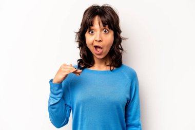 Beyaz arka planda izole edilmiş genç İspanyol kadın bir şeye gülüyor, elleriyle ağzını kapatıyor..