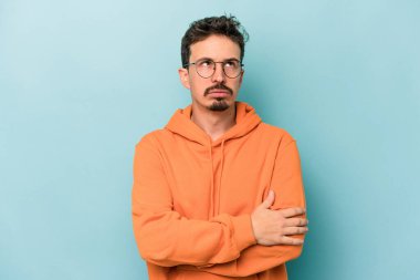 Mavi arka planda izole edilmiş genç beyaz adam tekrarlanan bir görevden yoruldu..