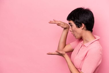 Pembe arka planda izole edilmiş genç beyaz kadın elleri arasında bir kopya alanı tutarken şok ve hayrete düştü..