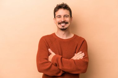 Beyazların arka planında izole edilmiş genç, kendinden emin, kararlılıkla kollarını kavuşturan bir adam..