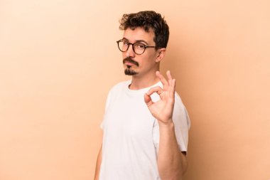 Beyazlı genç bir adam bej arka planda izole edilmiş bir şekilde göz açıp kapayıncaya kadar elinde iyi bir el hareketi tutuyor..