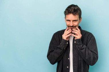 Kafkasyalı genç bir adam mavi arka planda izole edildi. Aklında bir plan kuruyor, bir fikir kuruyor..